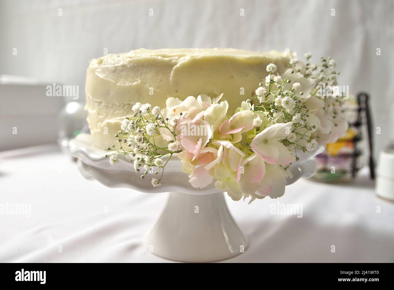 Gâteau de mariage blanc crème Buttercream sur le stand décoré avec des fleurs Hydrangeas et Babys Breath Banque D'Images