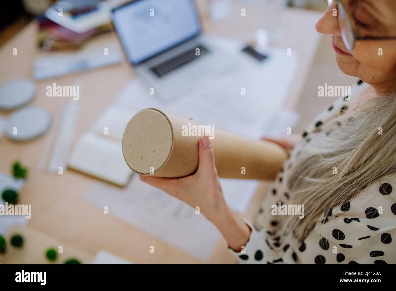 Gros plan d'une femme architecte tirant des plans roulés hors du tube dans le bureau. Banque D'Images