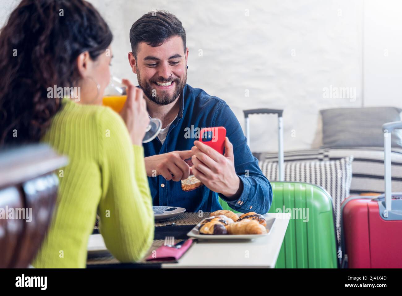 Couple touristique regardant le téléphone et prenant le petit déjeuner dans un restaurant de l'hôtel Banque D'Images