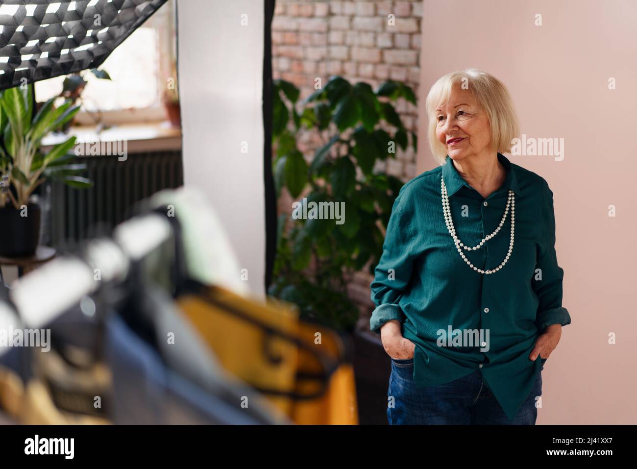 Femme âgée souriante posant dans une salle d'exposition élégante. Banque D'Images