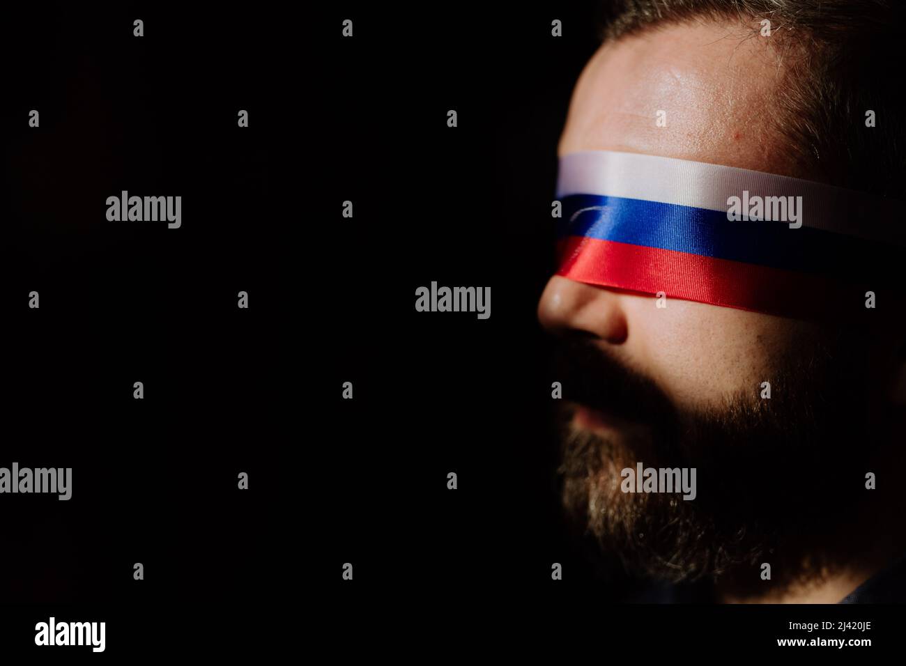 Homme avec le drapeau russe aveuglement sur fond noir, la propagande russe fermé les yeux des gens concept. Banque D'Images