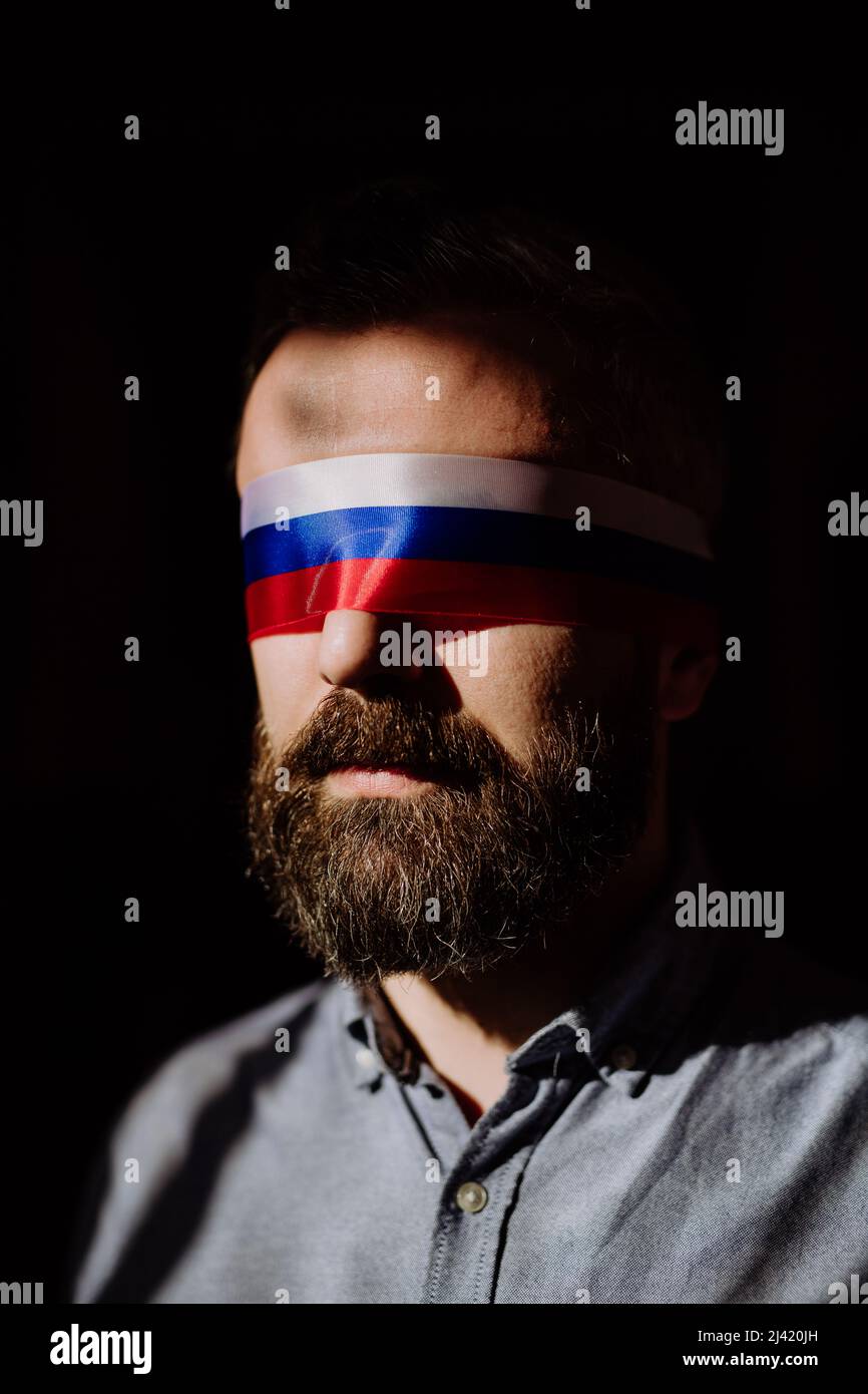 Homme avec le drapeau russe aveuglement sur fond noir, la propagande russe fermé les yeux des gens concept. Banque D'Images