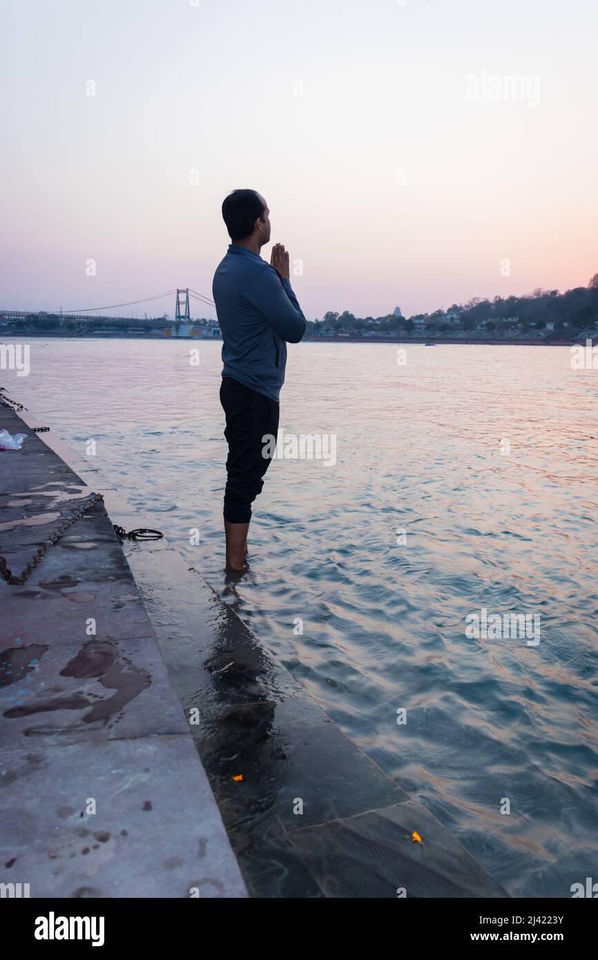 un jeune homme isolé en train de fouler le saint gange à la rive du fleuve à partir d'une image d'angle plat est pris à la rive du ganga rishikesh uttrakhhand inde. Banque D'Images