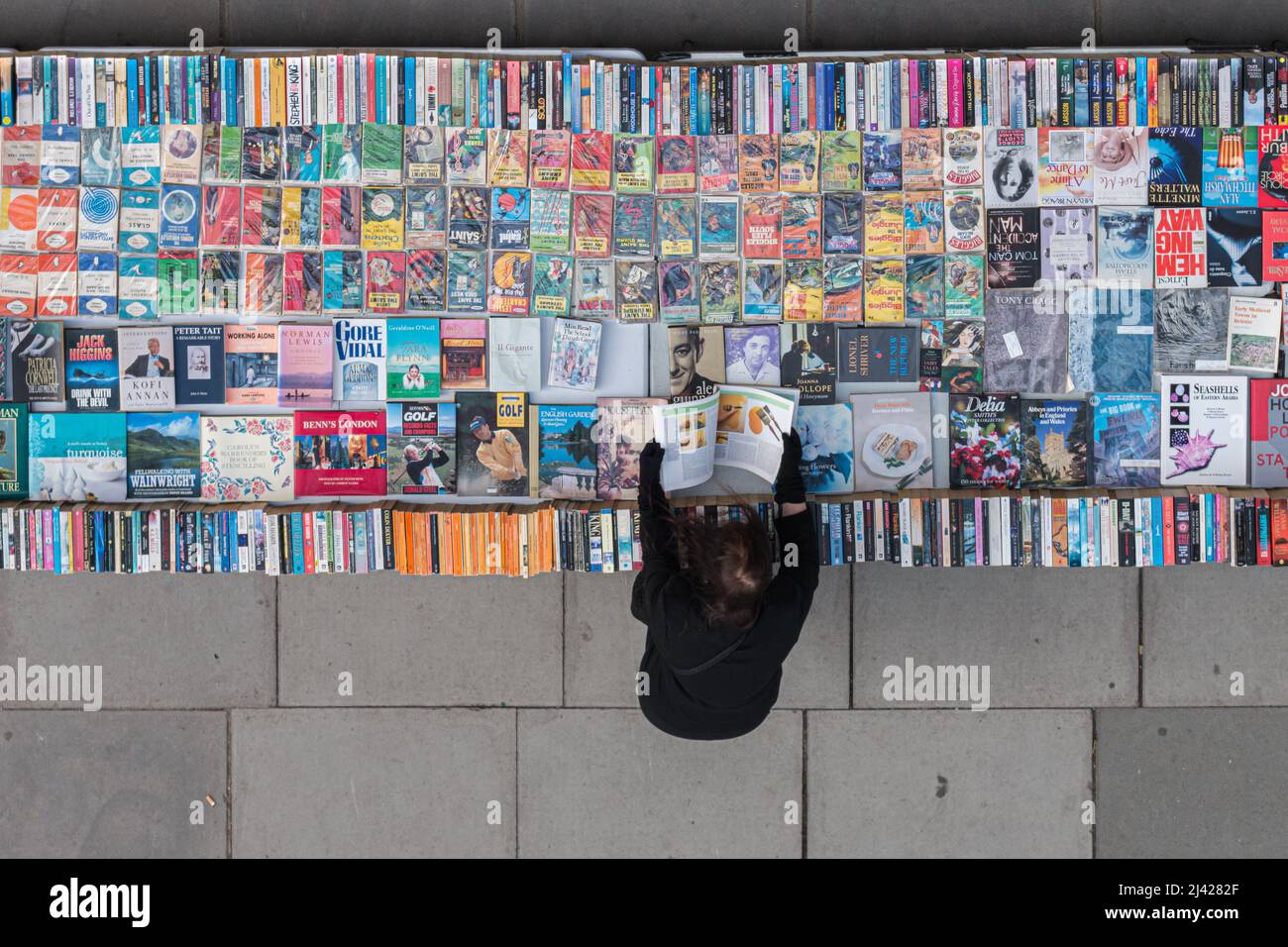 Londres, Royaume-Uni - 22 octobre, 2016: Femme célibataire feuilletant les pages d'un livre de seconde main dans le stand de librairie sur Southbank à Londres Banque D'Images