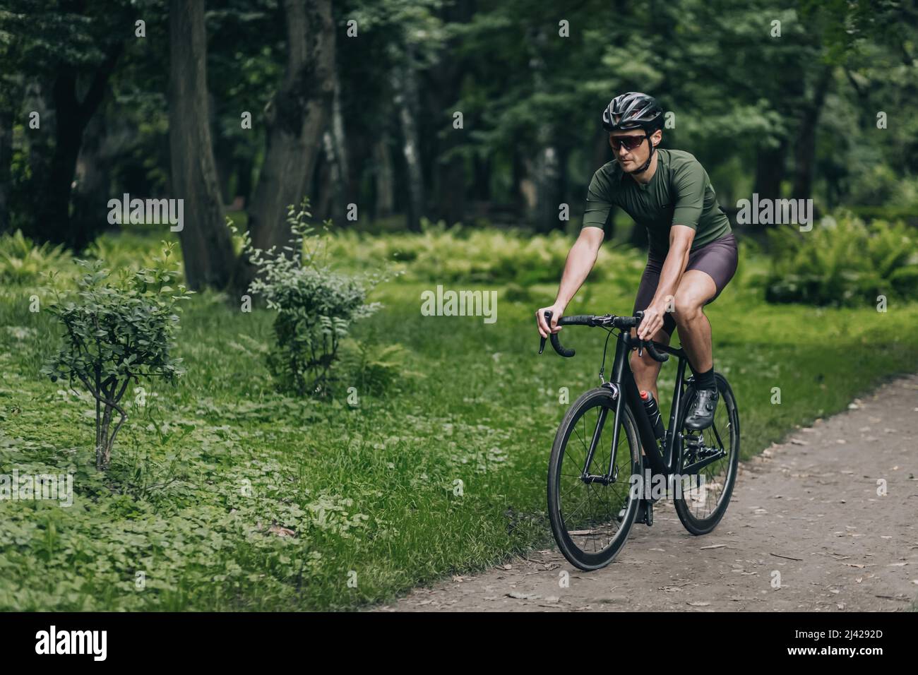 Sportif caucasien dans un casque de sécurité et des lunettes à miroir de vélo pendant la matinée à l'air frais. Un homme actif qui apprécie son passe-temps préféré lors d'un été vert Banque D'Images