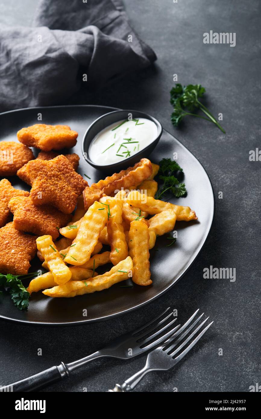 Fish Chips, restauration rapide britannique. Bâtonnets de poisson avec frites sur plaque noire sur fond de table noire. Cuisine traditionnelle britannique authentique ou Banque D'Images