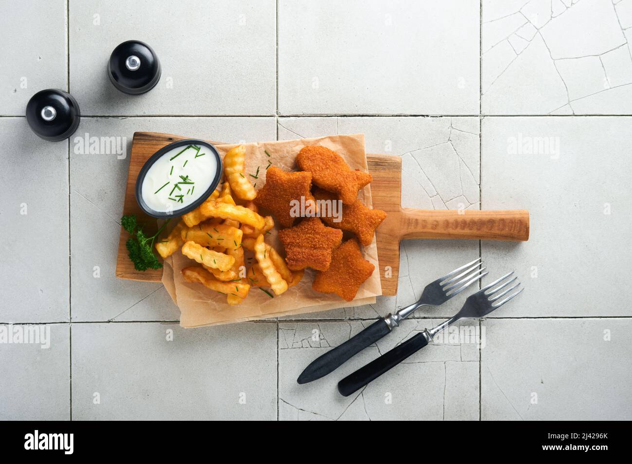 Fish Chips, restauration rapide britannique. Les bâtonnets de poisson aux frites sont fixés sur un panneau rustique, sur un fond de table de comptoir en carreaux gris craquelés. Tradition Banque D'Images