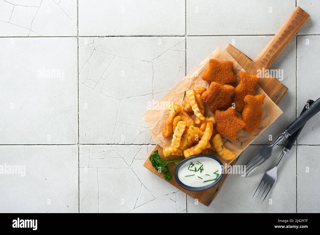 Fish Chips, restauration rapide britannique. Les bâtonnets de poisson aux frites sont fixés sur un panneau rustique, sur un fond de table de comptoir en carreaux gris craquelés. Tradition Banque D'Images
