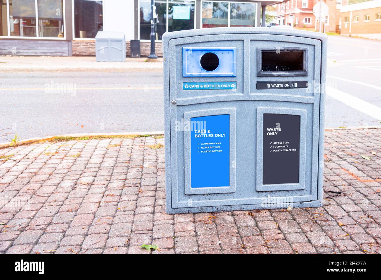 Bac de recyclage sur un trottoir en briques dans un centre-ville Banque D'Images