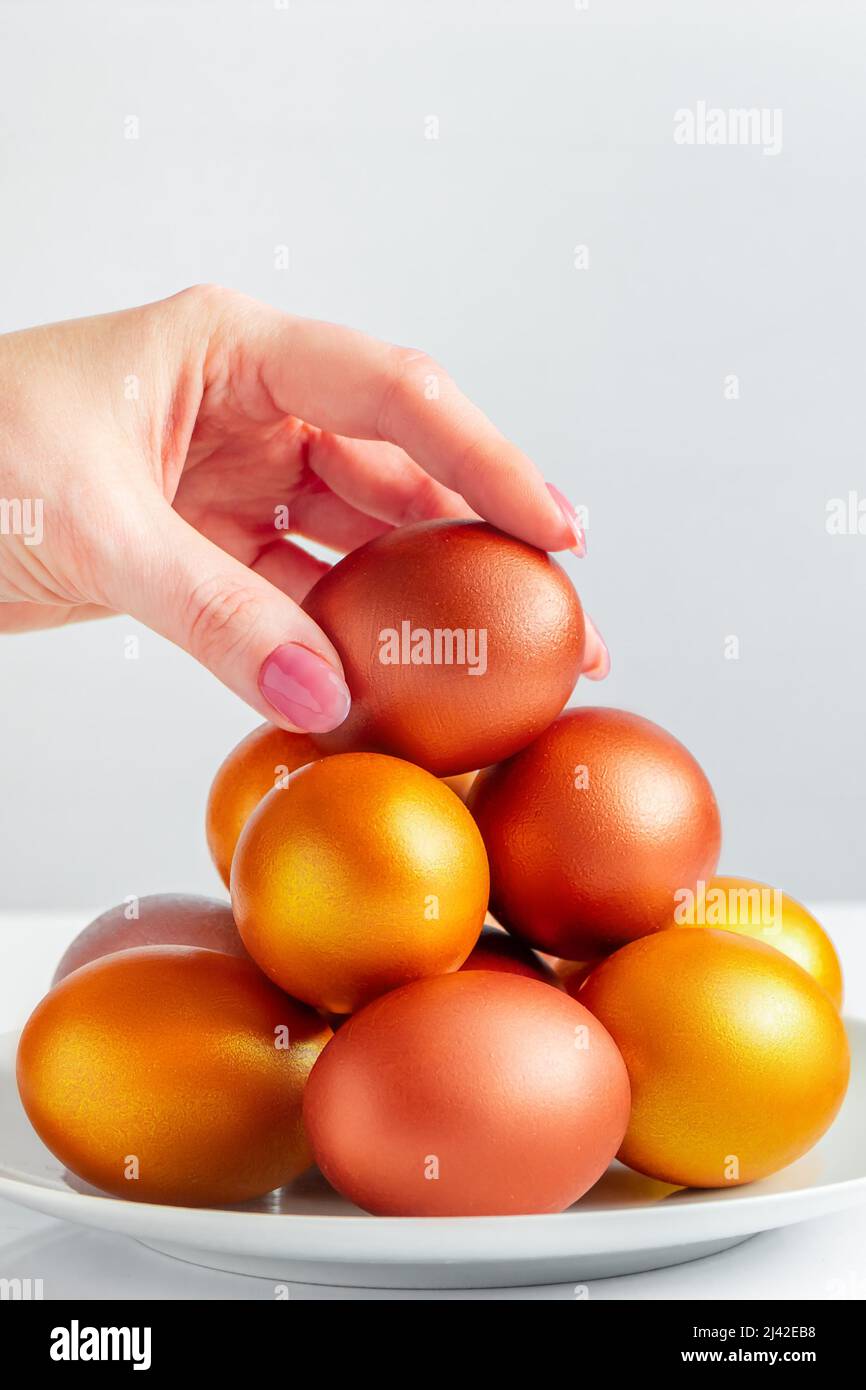 La femme met l'œuf de Pâques doré dans la pile. Concept de bonnes vacances. Banque D'Images