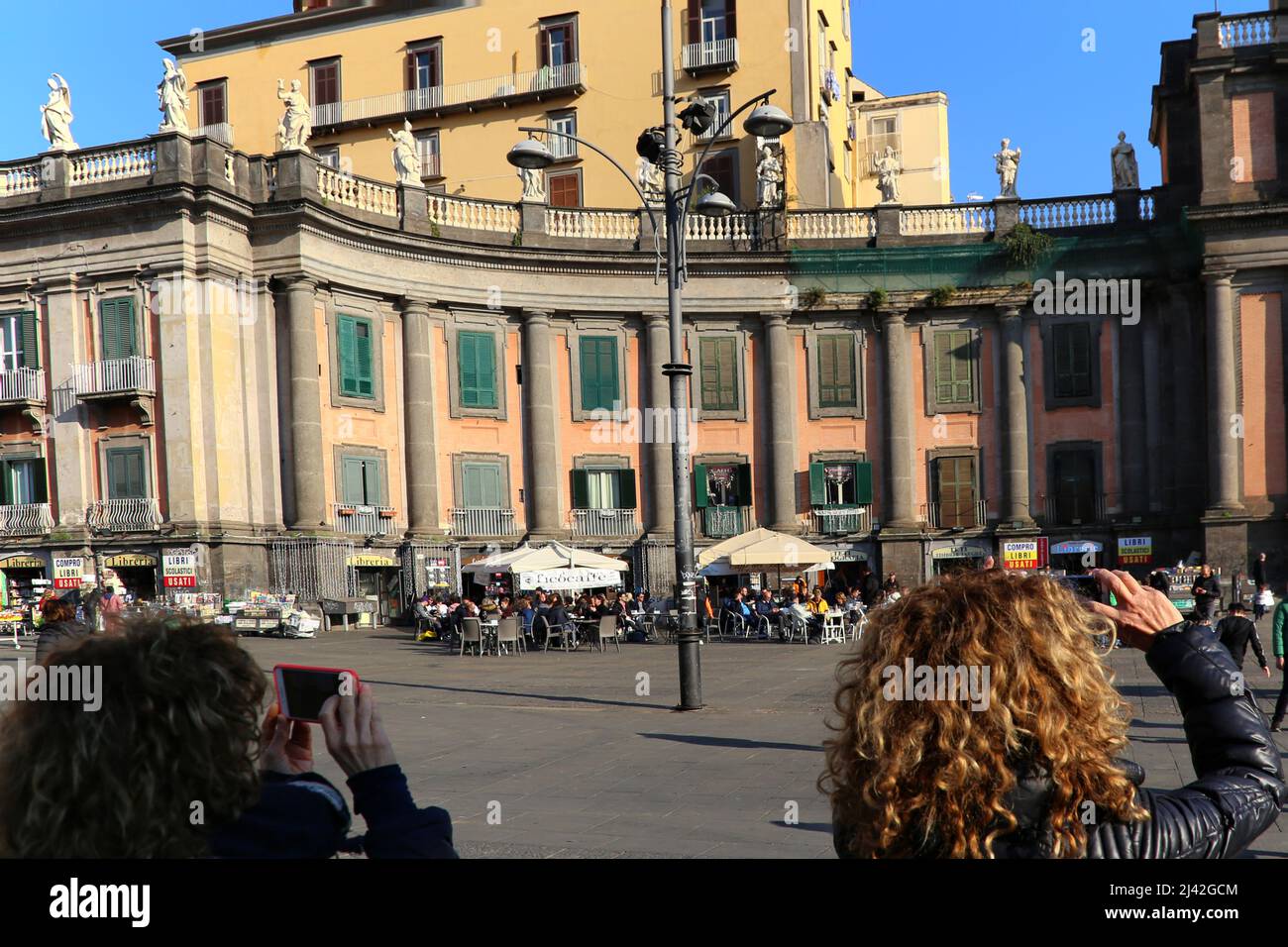 Naples, Italie - 3 janvier 2020. Vue arrière de deux femmes prenant des photos avec leur smartphone dans les bâtiments de Piazza Colombo, dans le centre historique Banque D'Images