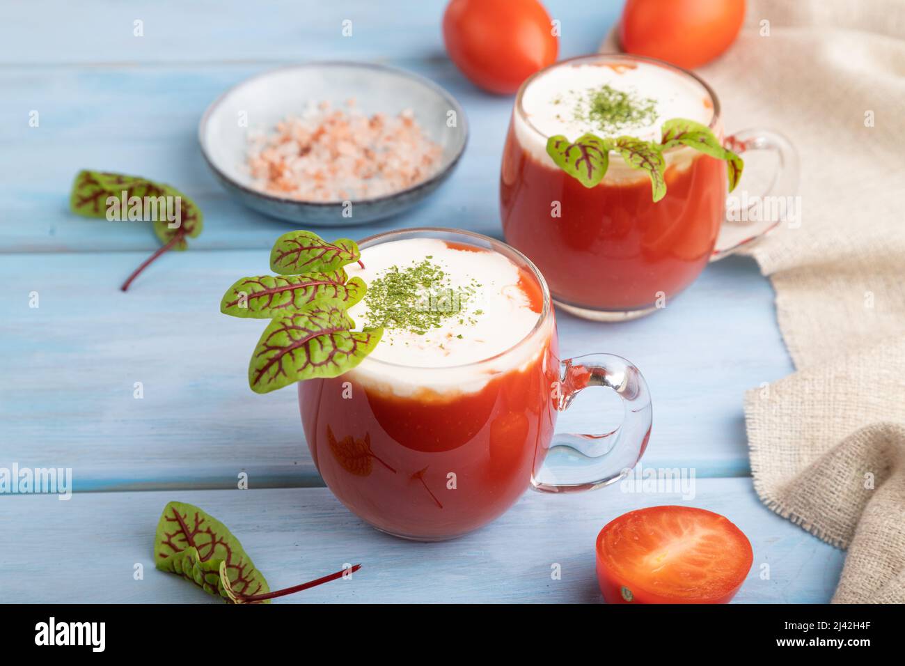 Jus de tomate avec sorrel, sel himalayan et crème aigre en verre sur fond de bois bleu avec textile lin. Concept de boisson saine. Vue latérale, fermer Banque D'Images
