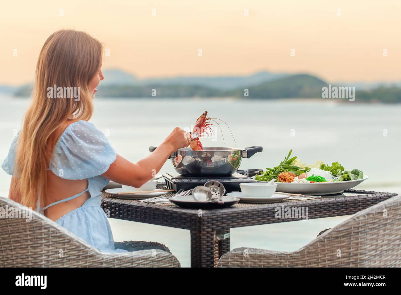 Femme cuisant et mangeant des fruits de mer frais et de la viande, plat traditionnel japonais Banque D'Images