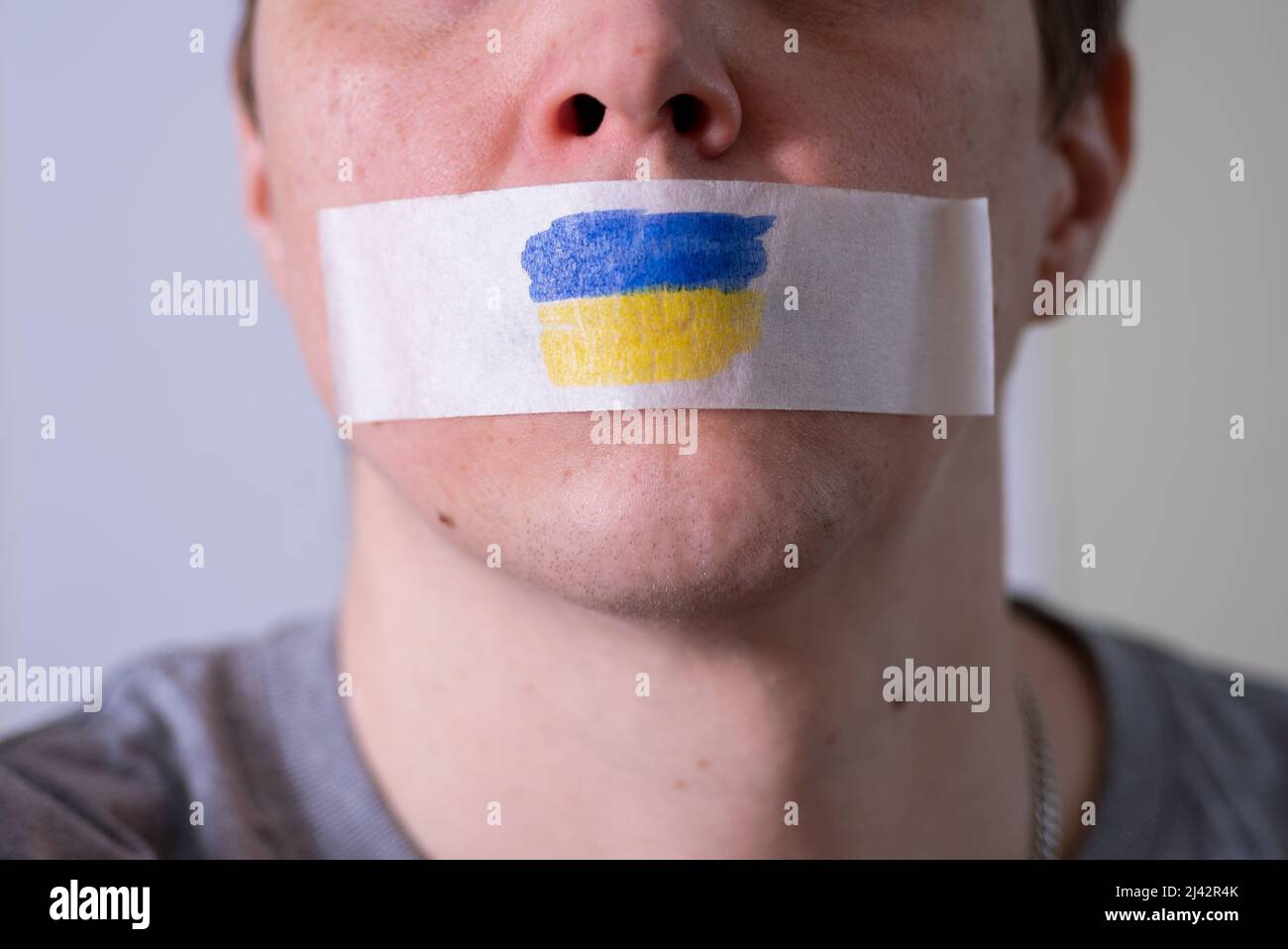 Homme caucasien avec ruban adhésif sur la bouche. Le drapeau de l'Ukraine sur la bande. Le concept de liberté d'expression dans les nouvelles du monde. Banque D'Images