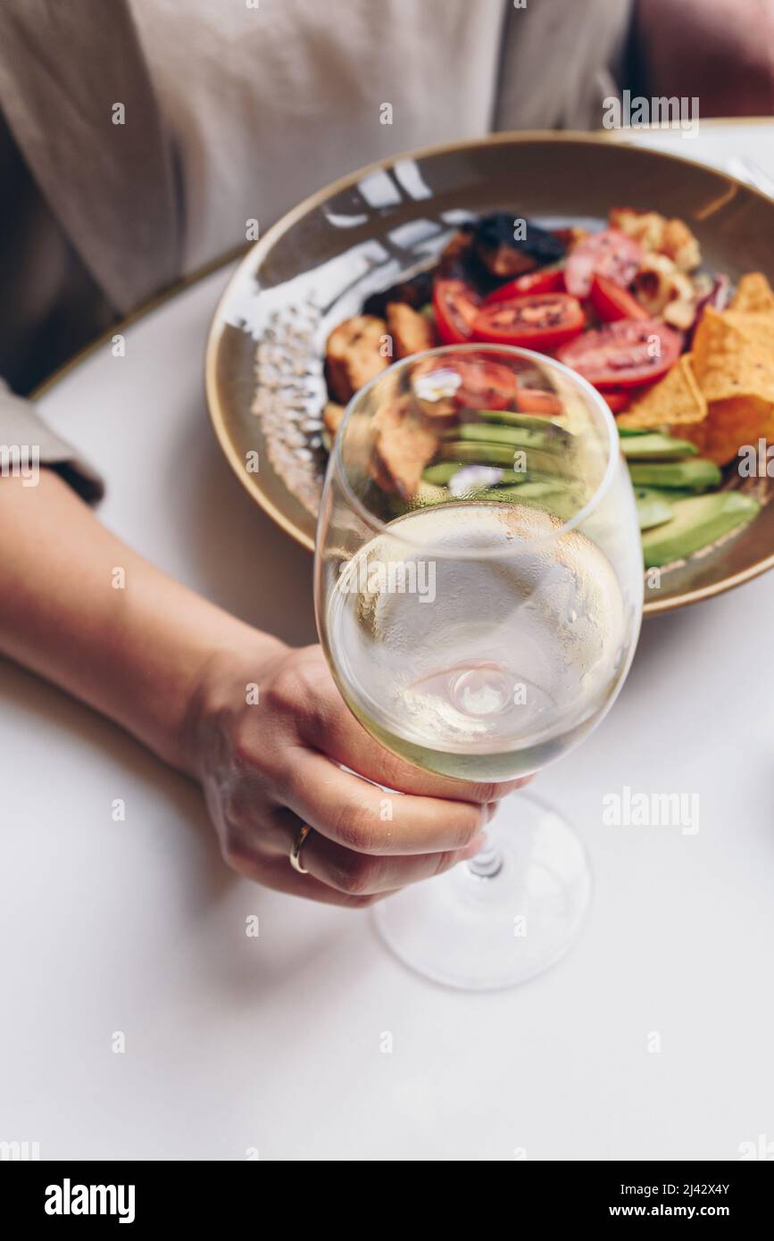 Femme ayant son déjeuner et elle tient un verre de vin blanc Banque D'Images