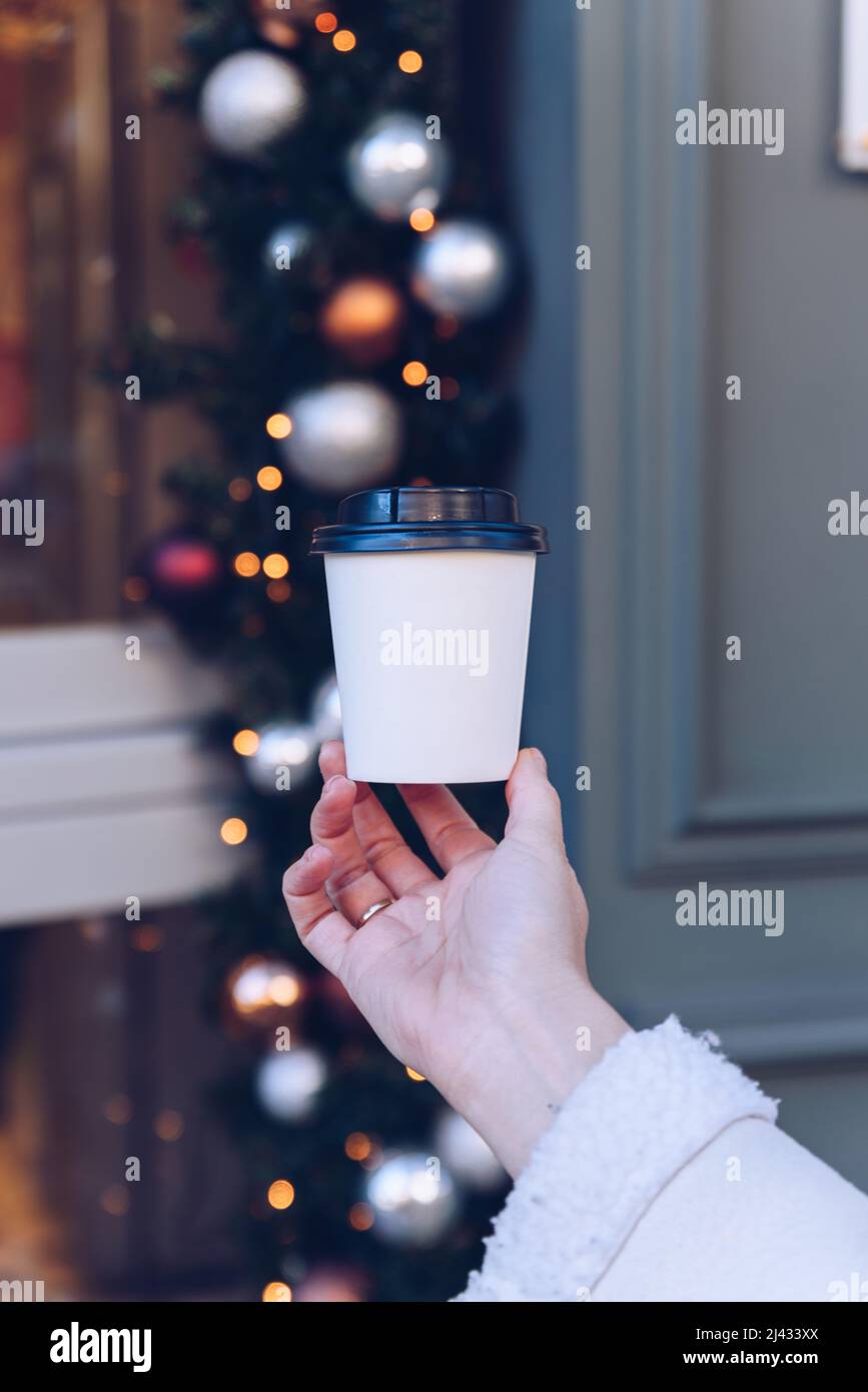 La main jeune femelle tient une tasse de papier de café, à emporter. Banque D'Images