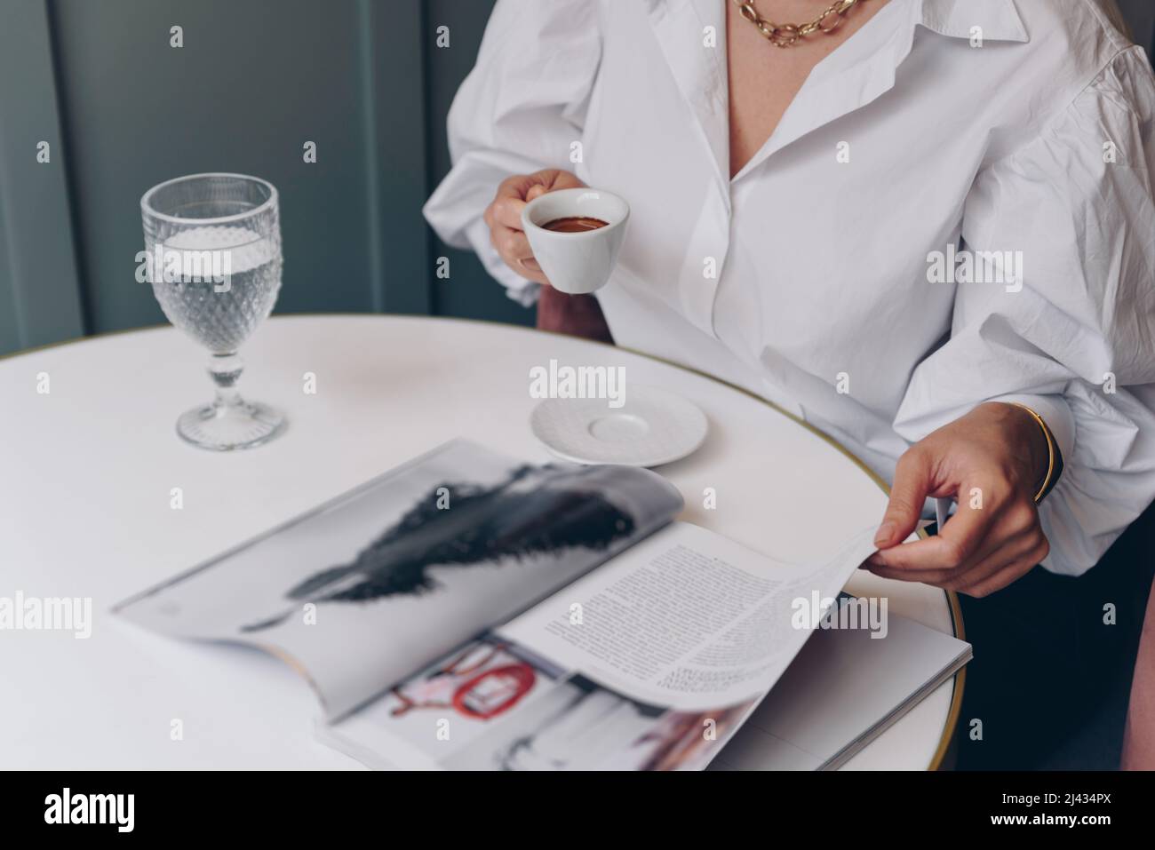 Jeune femme élégante qui boit du café au café, tout en lisant le magazine Banque D'Images