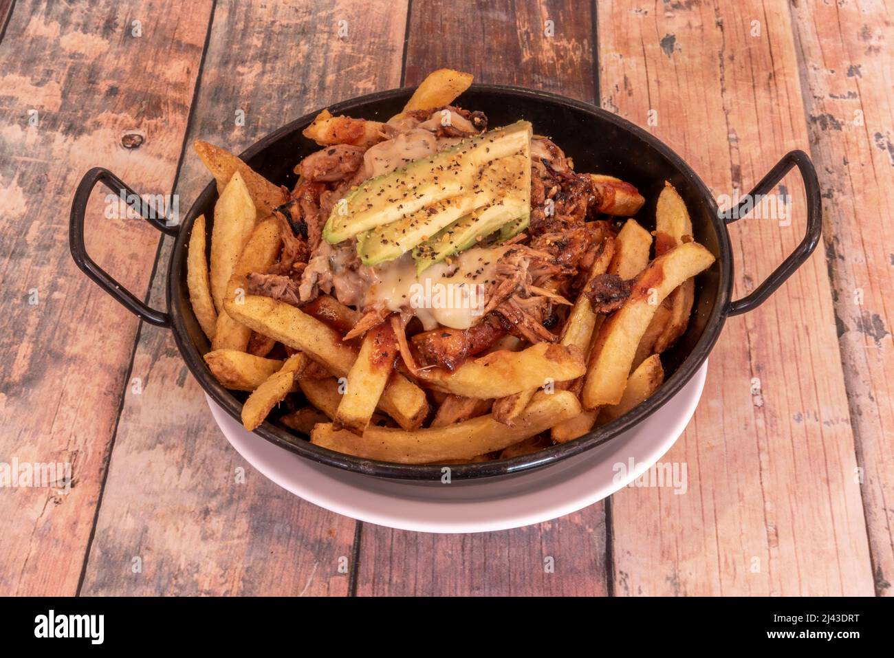Le porc tiré n'est rien de plus qu'un filet de porc mariné, cuit longtemps, accompagné d'un avocat, fromage fondu sur une tarte en PA émaillée Banque D'Images