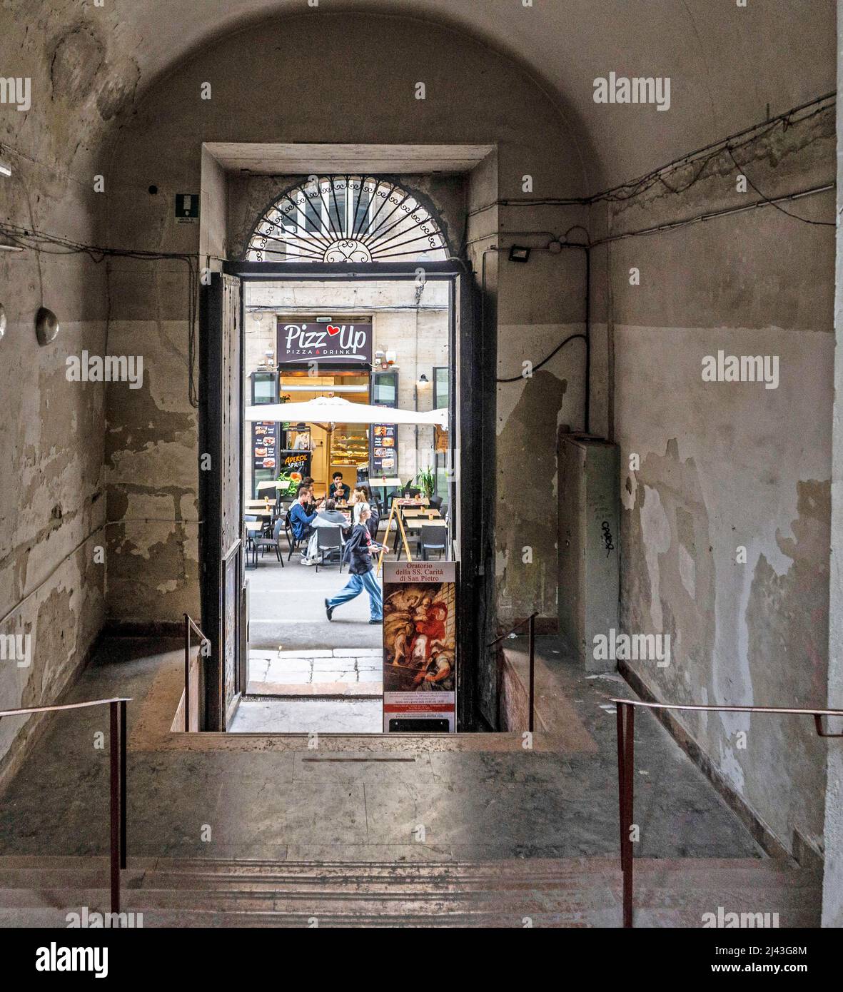 Les gens qui mangent de la pizza devant un magasin de pizza dans la via Maqueda, Palerme, Sicile, Italie, comme vu par une arche. Banque D'Images