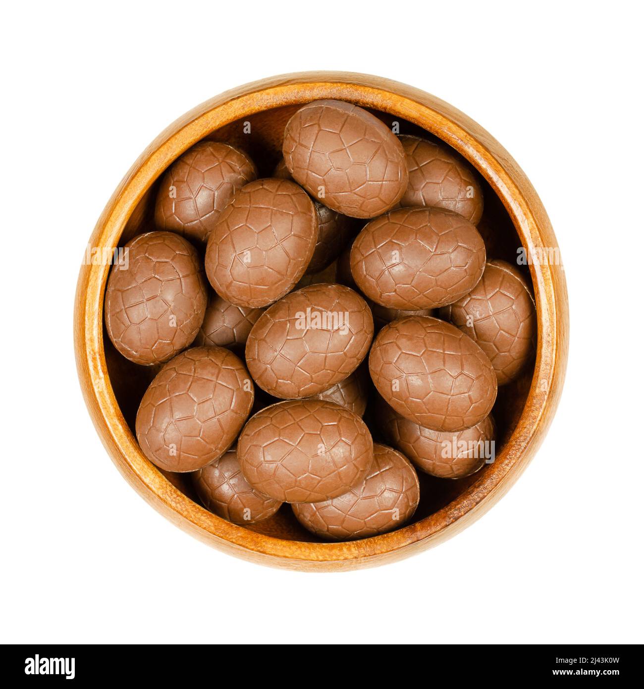 Lait chocolat oeufs de Pâques, dans un bol en bois. Mini œufs au chocolat, un sucrerie. Isolé, du dessus, sur fond blanc, macro photo alimentaire. Banque D'Images