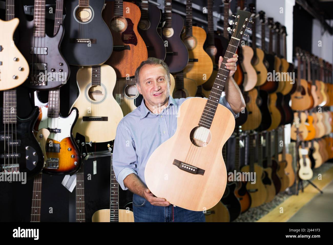 Homme mature qui choisit la guitare acoustique Banque D'Images