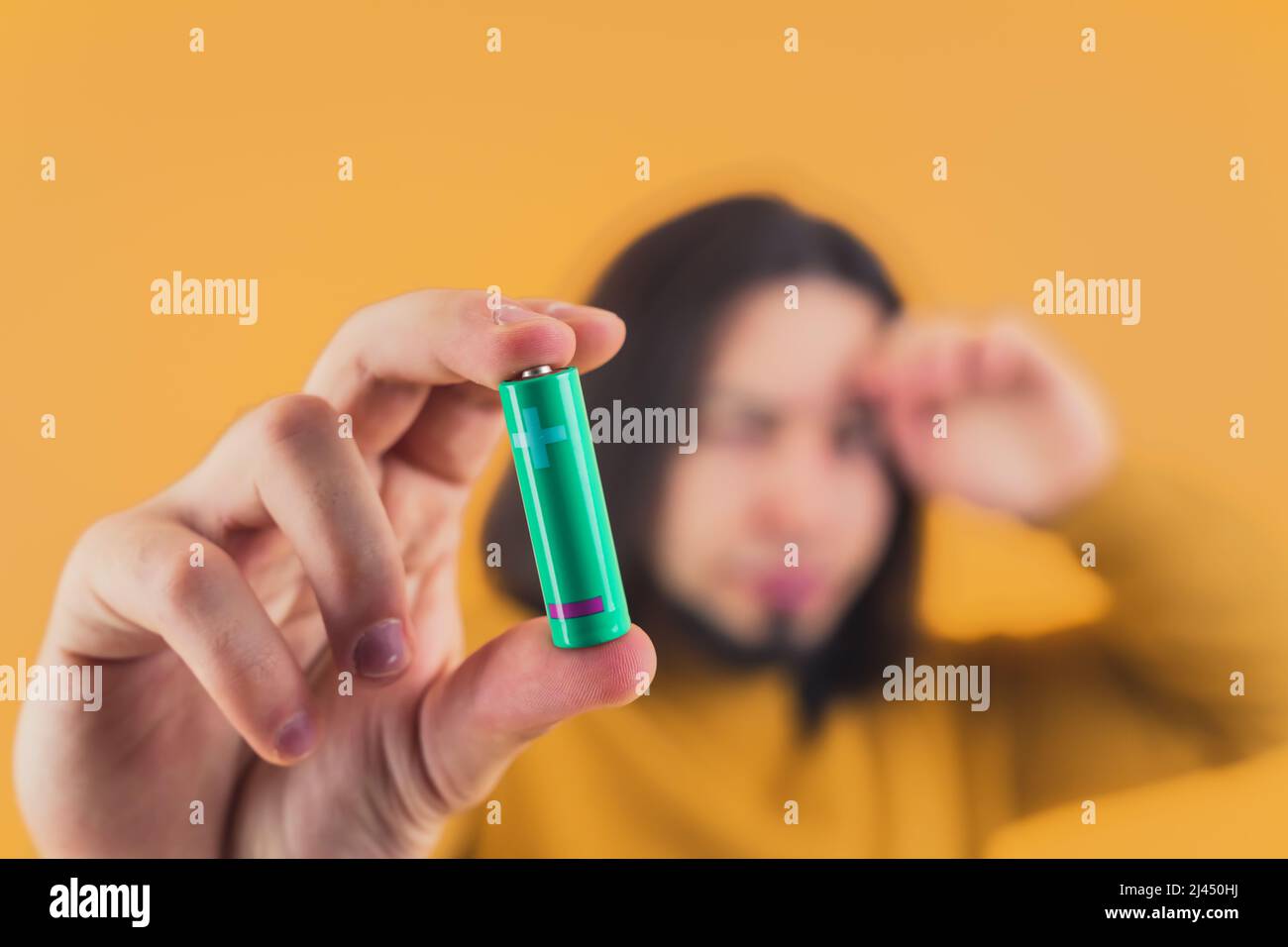 Homme mmillénaire à cheveux foncés montrant la batterie à l'appareil photo jaune arrière-plan copie espace studio tourné . Photo de haute qualité Banque D'Images