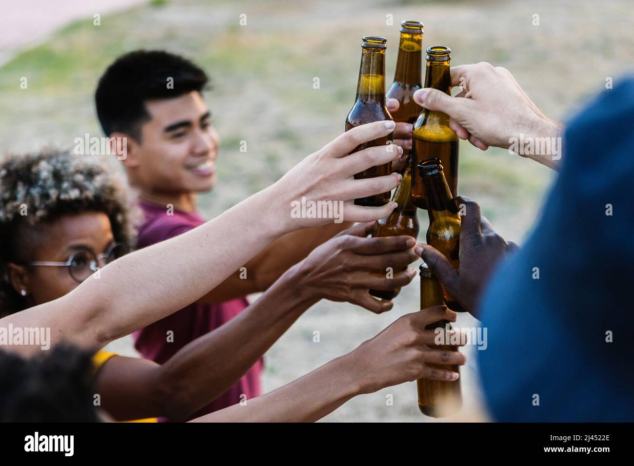 Groupe d'amis multiraciaux en dégustant des bouteilles de bière Banque D'Images