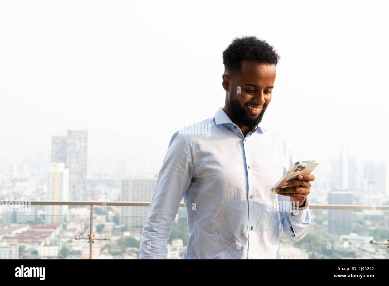 Portrait d'un beau jeune homme africain à l'extérieur à l'aide d'un téléphone portable Banque D'Images