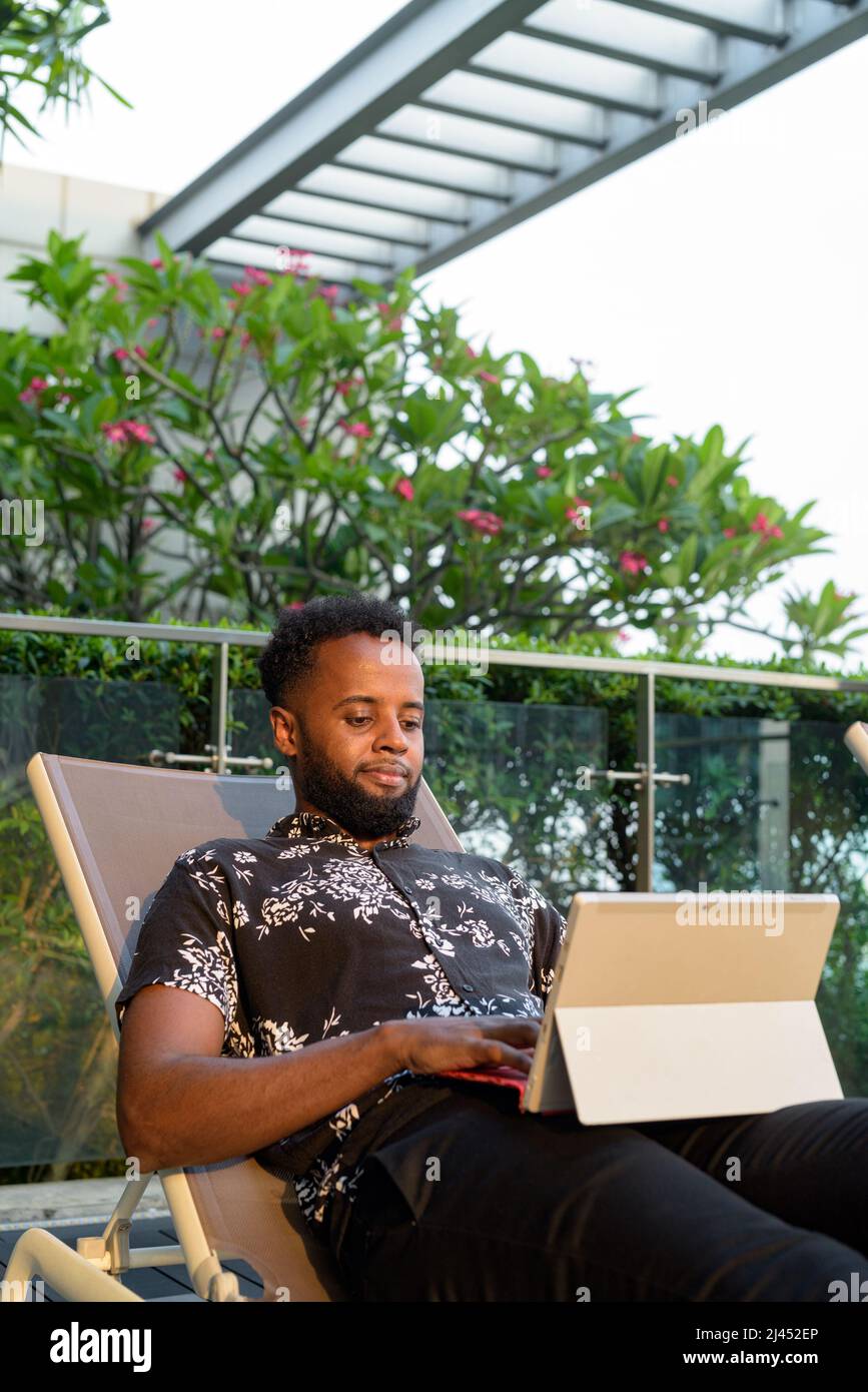 Portrait d'un beau jeune homme africain à l'extérieur à l'aide d'un téléphone portable Banque D'Images