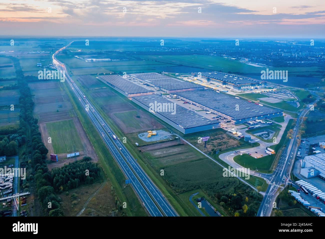 Vue imprenable sur le coucher du soleil au-dessus d'un entrepôt et les routes menant à l'horizon. Banque D'Images