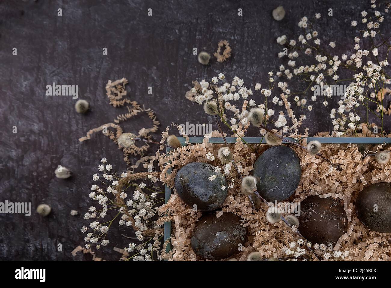 Composition de Pâques avec œufs de couleur foncée dans une boîte en bois. Branche de saule. Le concept minimal de Pâques. Une carte de Pâques avec une place pour le texte. Banque D'Images