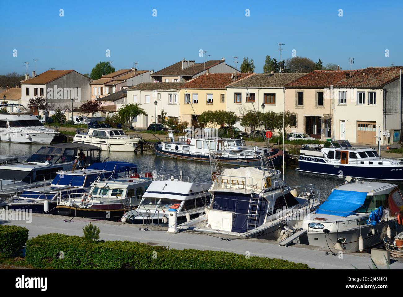 Vue sur les bateaux-canaux et les bateaux-rivières sur le canal Rhône-Sète et les maisons en bord de canalside à Aigues-mortes Gard France Banque D'Images