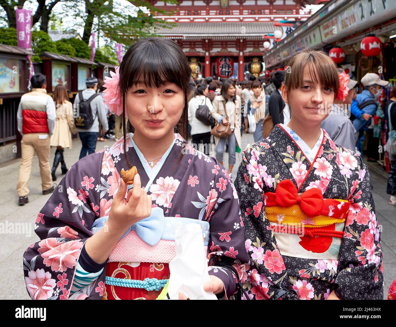 Japon. Tokyo. Une fille japonaise goûtant des bonbons dans les rues d'Asakusa avec son ami occidental Banque D'Images