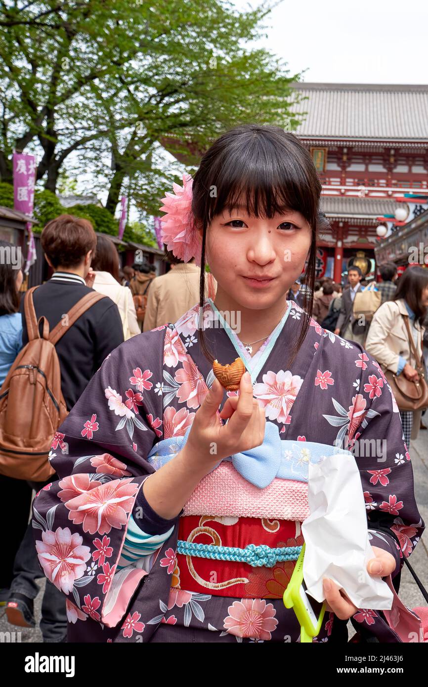 Japon. Tokyo. Une fille goûtant des bonbons dans les rues d'Asakusa Banque D'Images