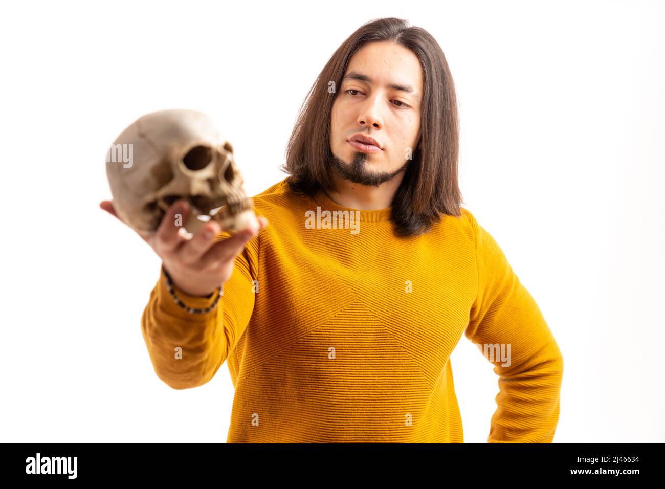 Le jeune homme caucasien barbu tient le crâne et le regarde fond blanc studio tourné isolé . Photo de haute qualité Banque D'Images