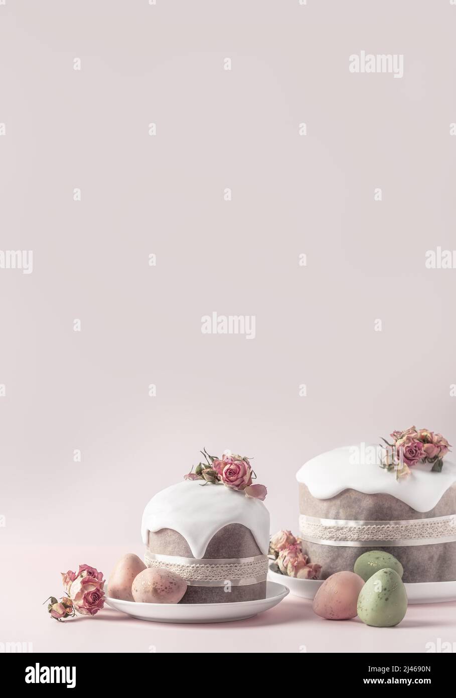 Gâteaux de Pâques émaillés décorés de fleurs de rose de thé sur fond rose pastel. Composition de Pâques avec gâteaux, roses et œufs au chocolat. Arrière-plan de Pâques avec espace de copie pour votre conception. Banque D'Images
