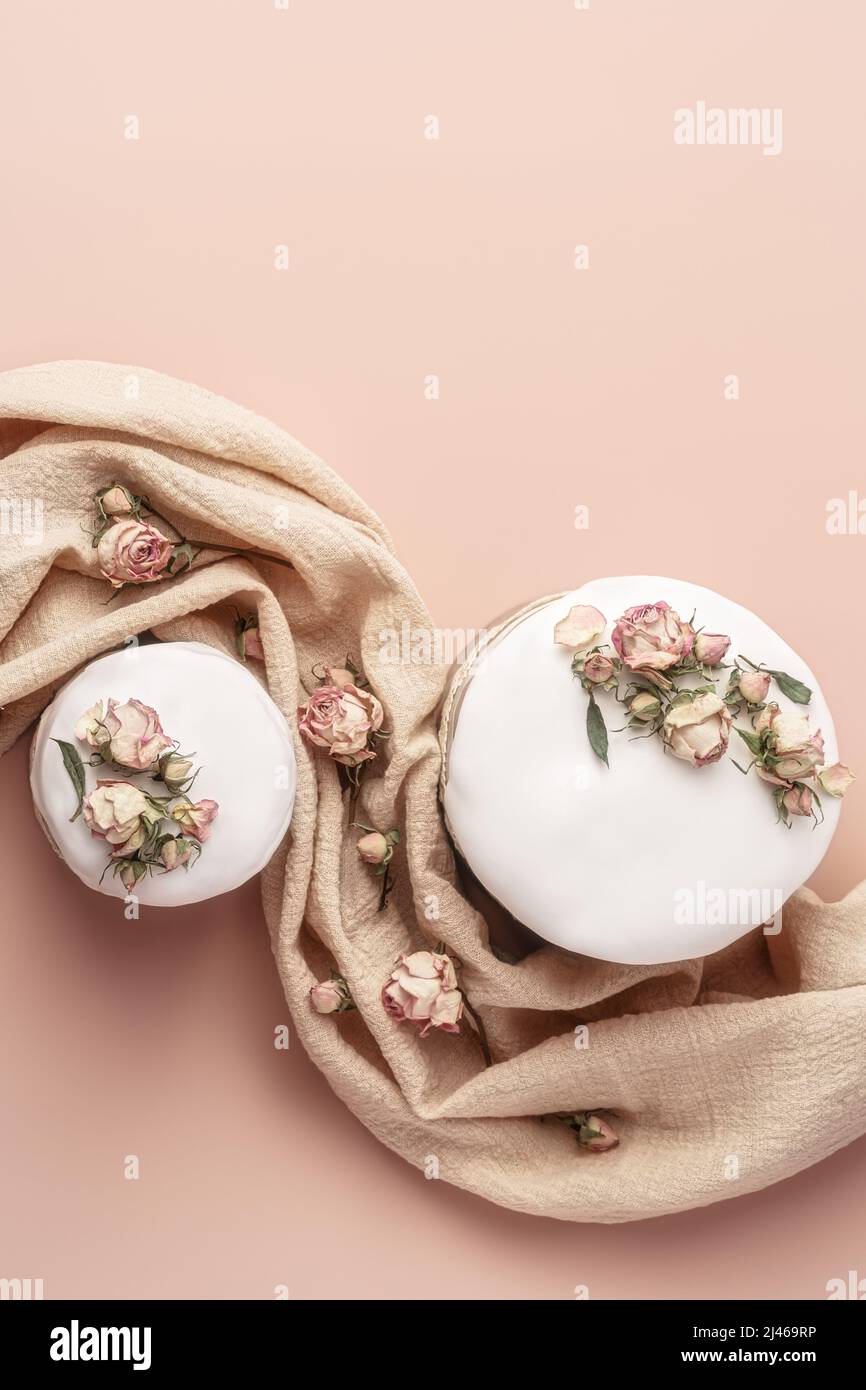 Gâteaux de Pâques émaillés décorés de fleurs de rose de thé sur fond pastel. Composition de Pâques avec gâteaux, roses et serviette. Arrière-plan de Pâques avec espace de copie pour votre conception. Banque D'Images