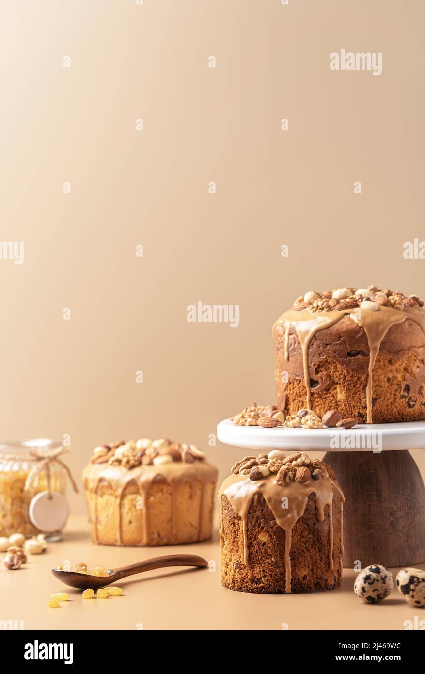 Gâteaux de Pâques émaillés de caramel décorés de noix sur fond pastel. Composition de Pâques avec gâteaux, noix, raisins secs et œufs de caille. Arrière-plan de Pâques avec espace de copie pour votre conception. Banque D'Images