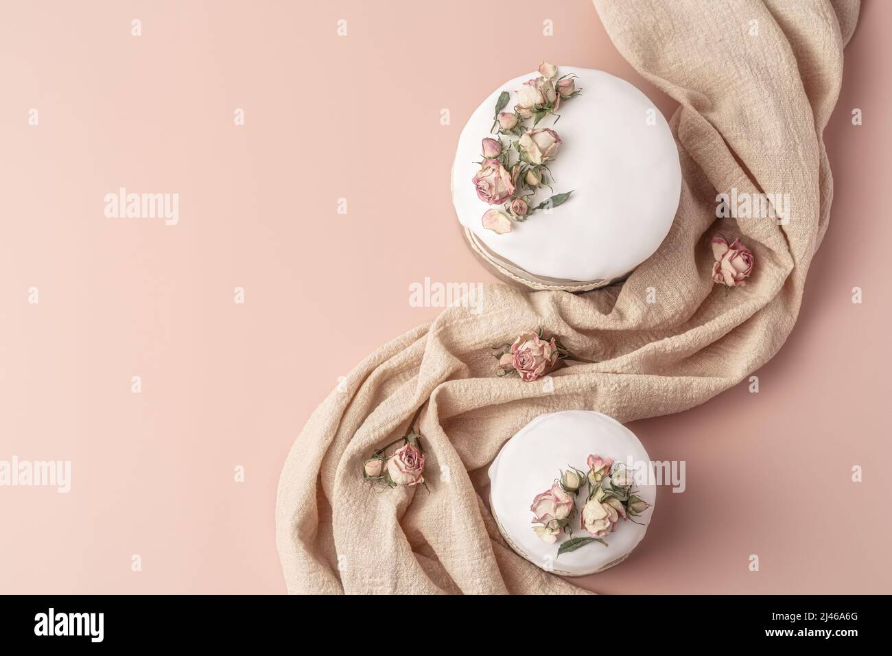 Gâteaux de Pâques émaillés décorés de fleurs de rose de thé sur fond pastel. Composition de Pâques avec gâteaux, roses et serviette. Arrière-plan de Pâques avec espace de copie pour votre conception. Banque D'Images