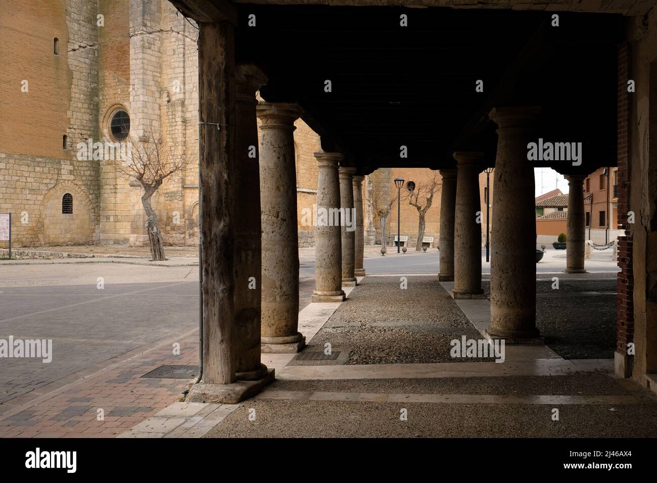 En regardant par les piliers des bâtiments pierés de la Plaza Mayor, Becerril de Campos, Espagne, vers l'Iglesia Parroquial de Santa Eugenia Banque D'Images