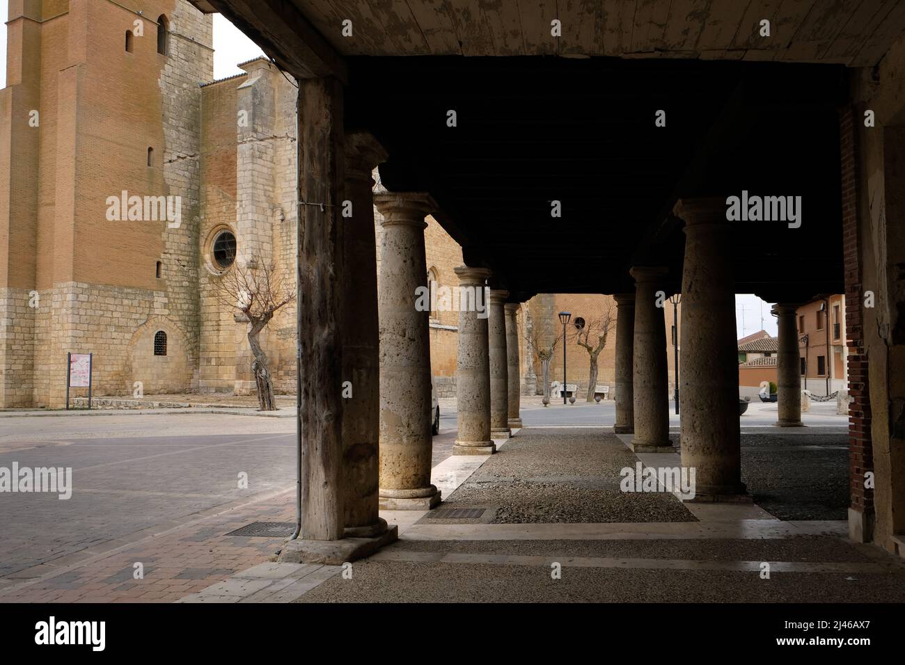 En regardant par les piliers des bâtiments pierés de la Plaza Mayor, Becerril de Campos, Espagne, vers l'Iglesia Parroquial de Santa Eugenia Banque D'Images