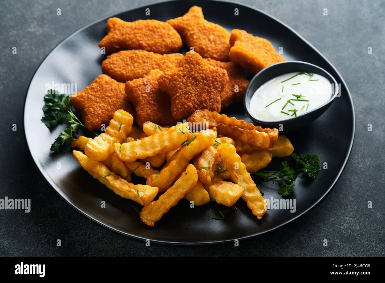 Fish Chips, restauration rapide britannique. Bâtonnets de poisson avec frites sur plaque noire sur fond de table noire. Cuisine traditionnelle britannique authentique ou Banque D'Images