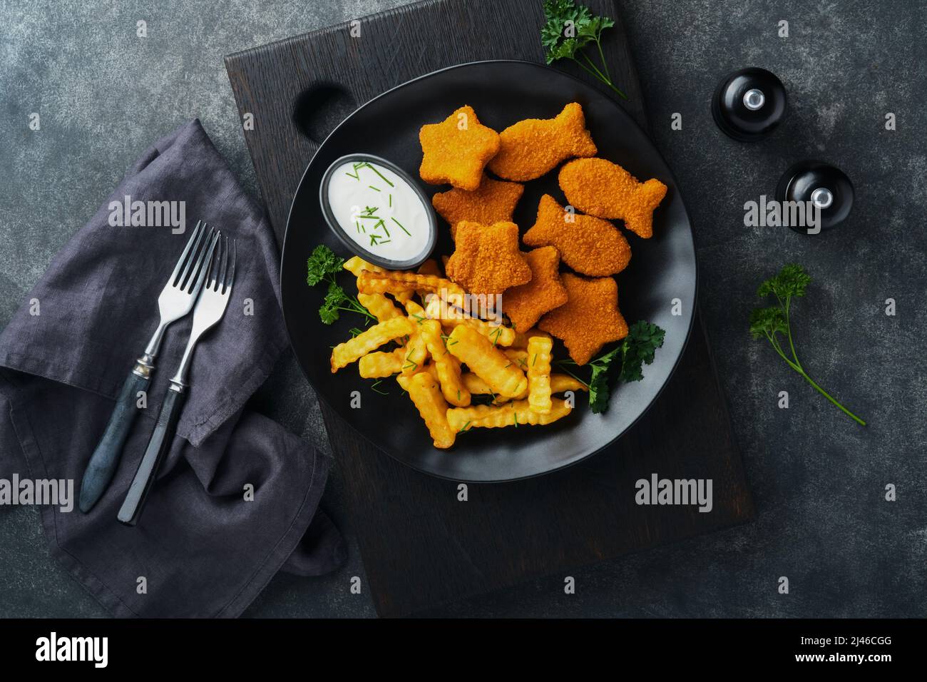 Fish Chips, restauration rapide britannique. Bâtonnets de poisson avec frites sur plaque noire sur fond de table noire. Cuisine traditionnelle britannique authentique ou Banque D'Images