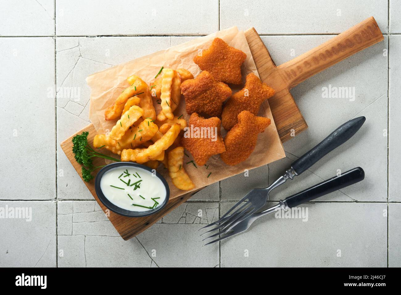 Fish Chips, restauration rapide britannique. Les bâtonnets de poisson aux frites sont fixés sur un panneau rustique, sur un fond de table de comptoir en carreaux gris craquelés. Tradition Banque D'Images
