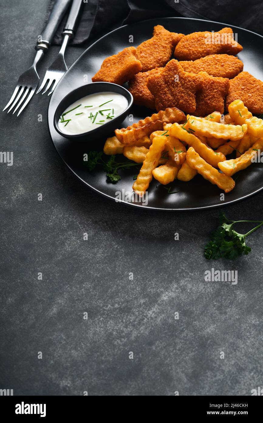 Fish Chips, restauration rapide britannique. Bâtonnets de poisson avec frites sur plaque noire sur fond de table noire. Cuisine traditionnelle britannique authentique ou Banque D'Images