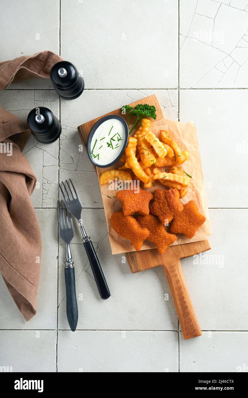 Fish Chips, restauration rapide britannique. Les bâtonnets de poisson aux frites sont fixés sur un panneau rustique, sur un fond de table de comptoir en carreaux gris craquelés. Tradition Banque D'Images