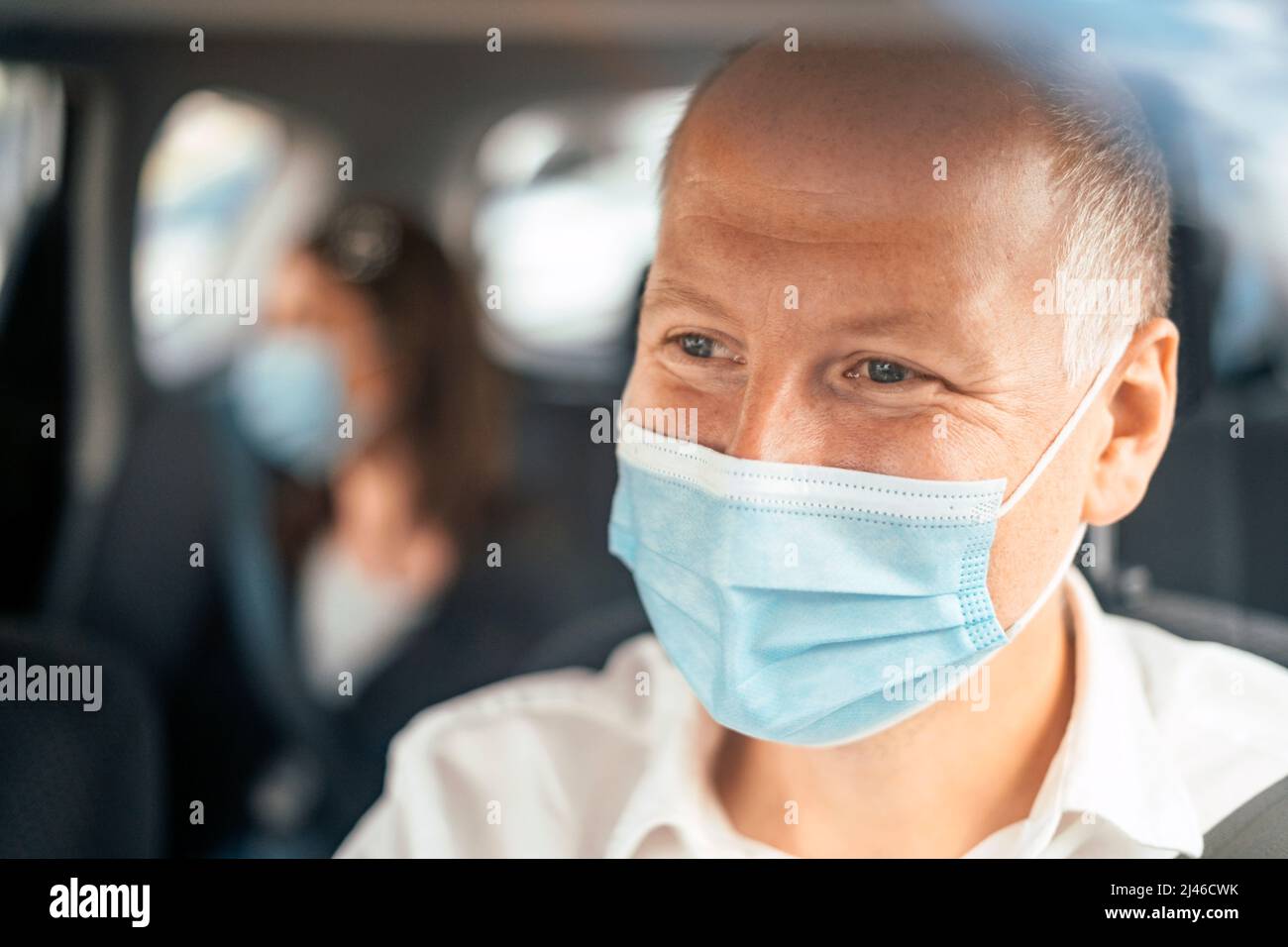 Un chauffeur de taxi heureux portant un masque et le passager sur le siège arrière de la voiture en arrière-plan Banque D'Images