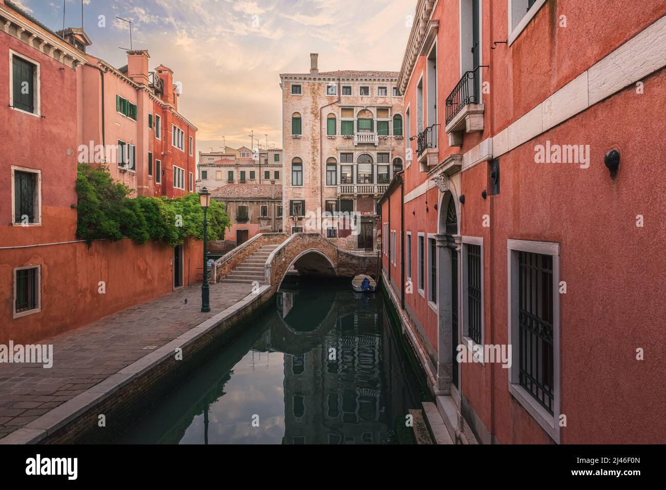 Venise, Italie. Vue au lever du soleil sur la rue médiévale vénitienne avec maisons anciennes et pont sur le canal d'eau avec bateau à Venise, Vénétie, Italie Banque D'Images
