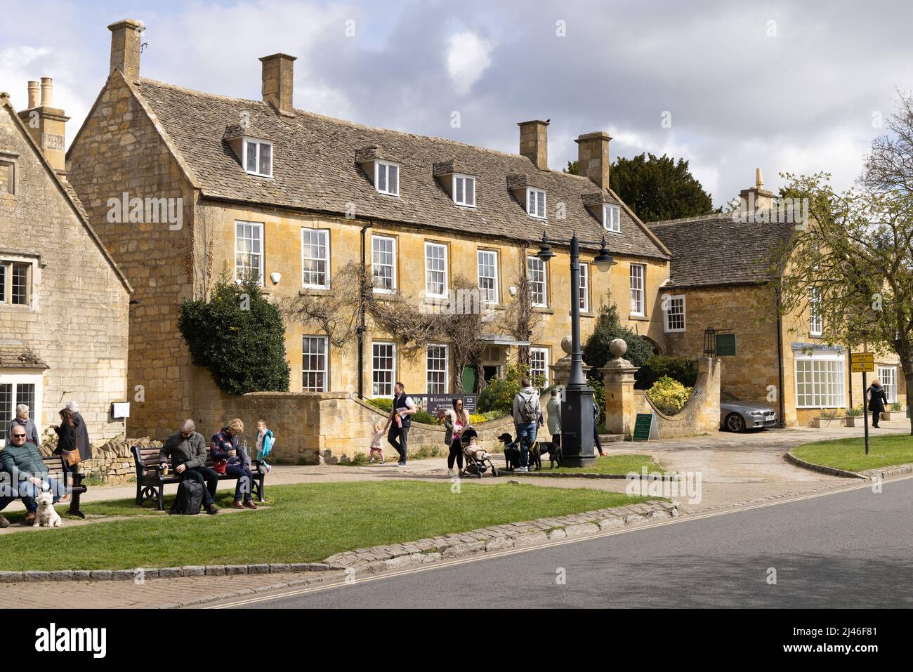 Village d'Angleterre - scène de rue; personnes profitant du soleil de printemps sur High Street, Broadway Village, les Cotswolds, Worcestershire Royaume-Uni Banque D'Images