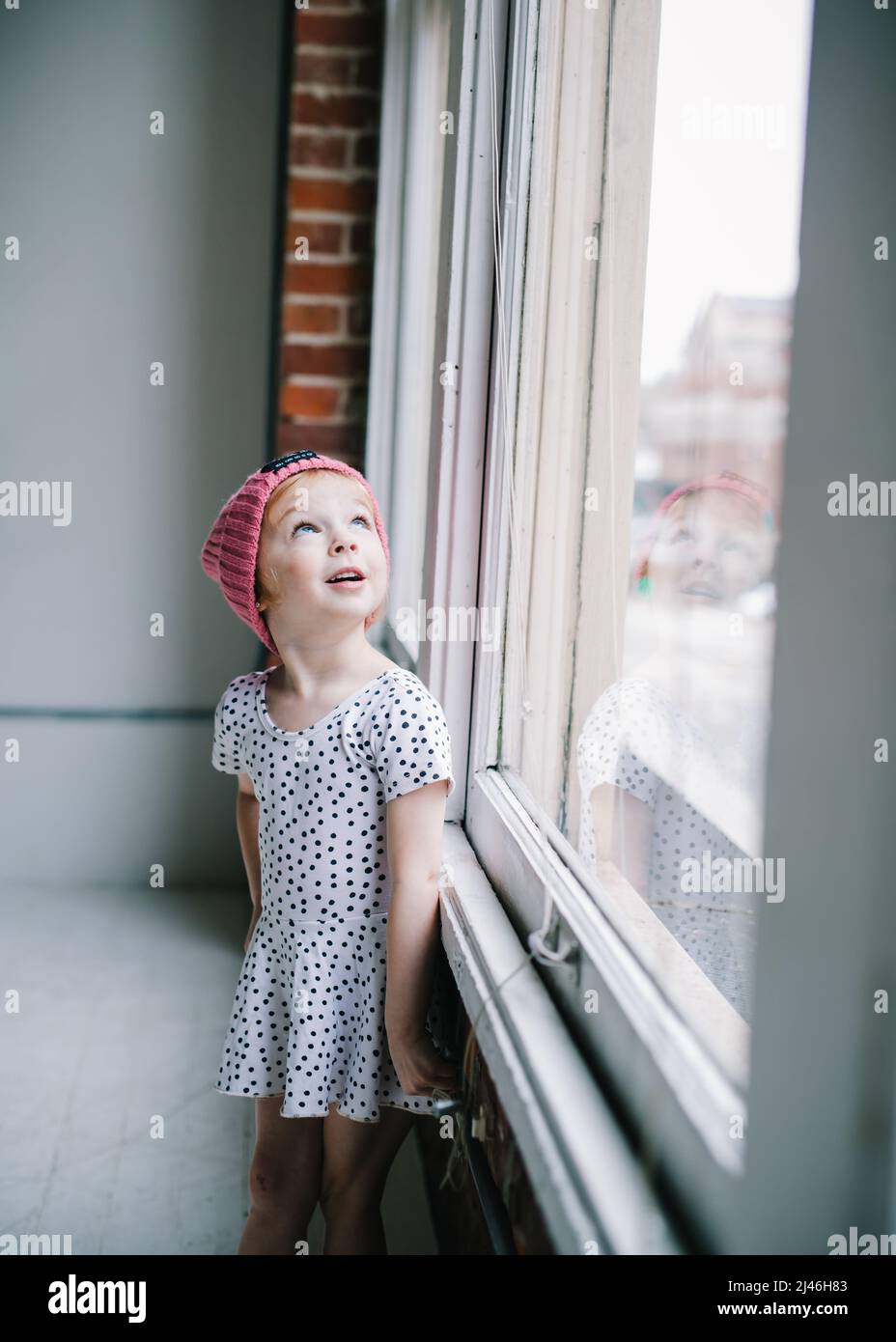 petite fille en robe à pois regardant la fenêtre derrière elle Photo Stock  - Alamy